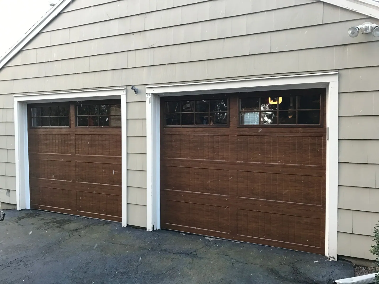 Two wood-look carriage doors with windows on a two-car garage